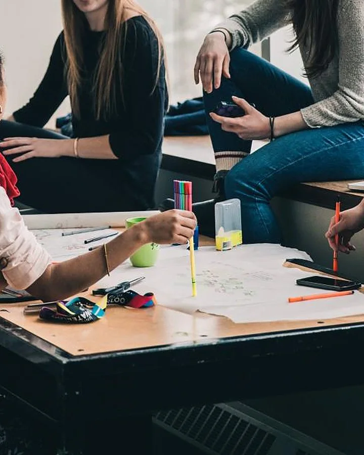 A group working together around a table covered in plans and markers